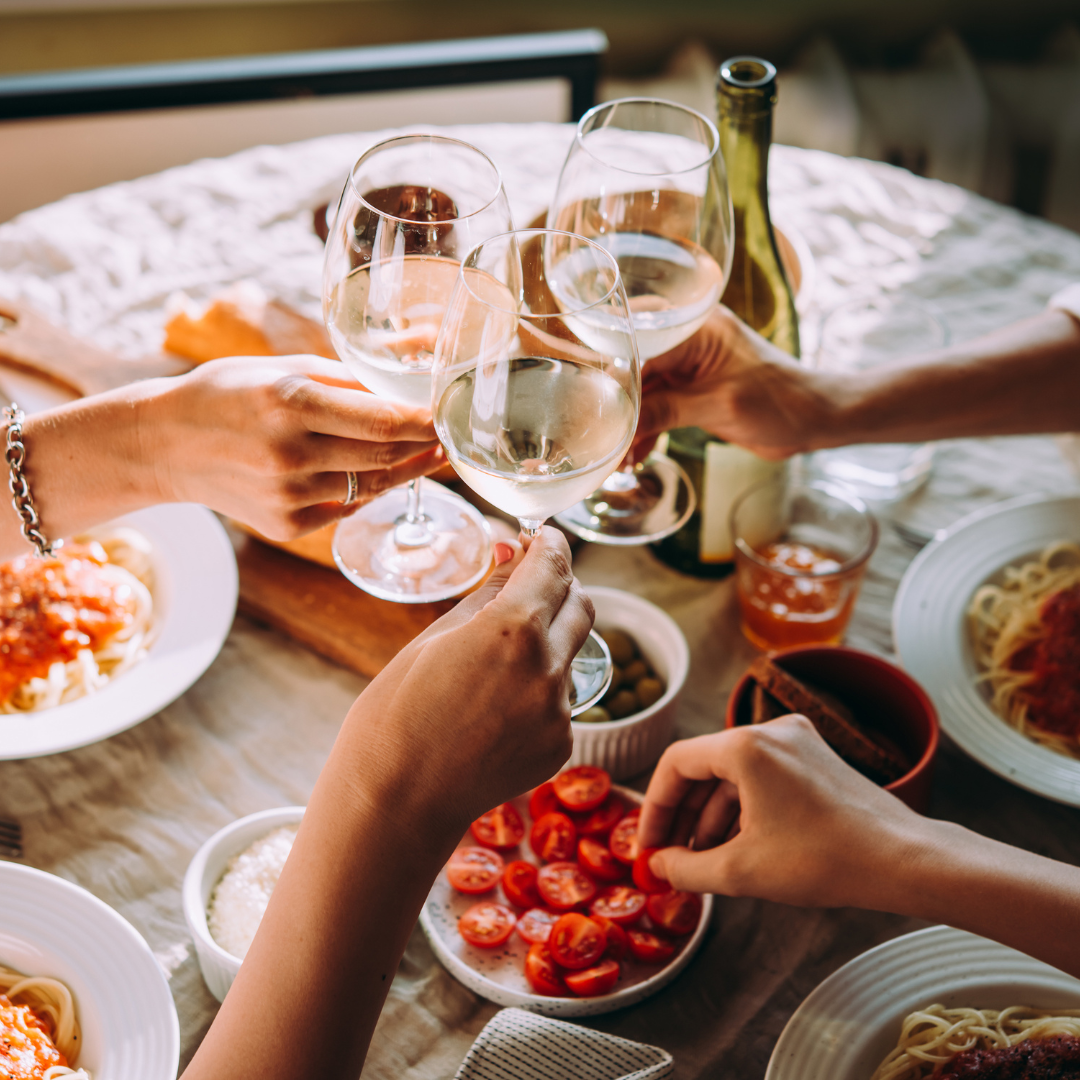 Peop;e cheersing white wine glasses above italian food at the Boutique Producer Wine Dinner at Park City Wine Festival.
